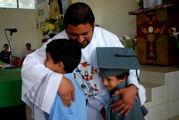 A pastor hugs two young boys